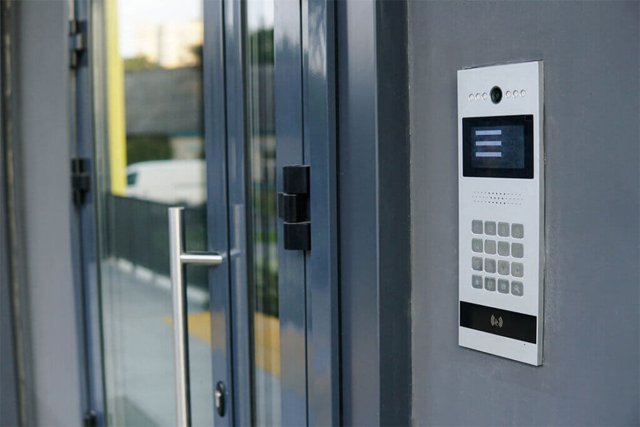 Gray commercial glass door with metal handle, keypad access panel on the side.