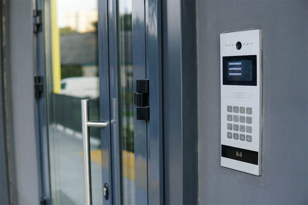 Gray commercial glass door with metal handle, keypad access panel on the side.
