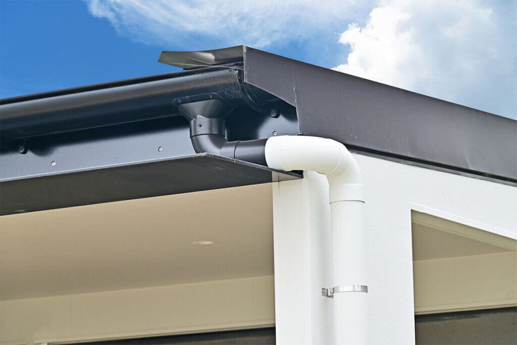 Black and white gutter system on modern building against blue sky.