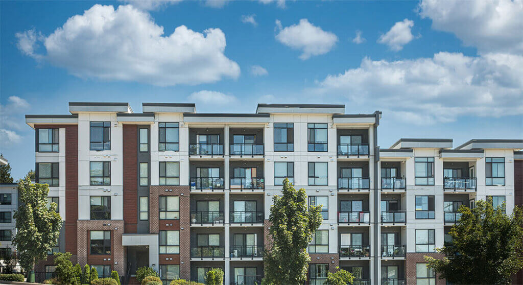 Modern commercial property with brick and white facade, four stories, under blue sky.