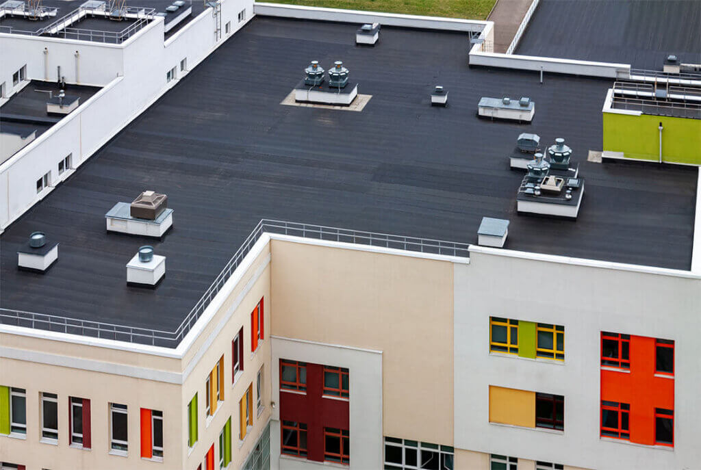 Flat black roof on a colorful commercial building by roofing contractors.